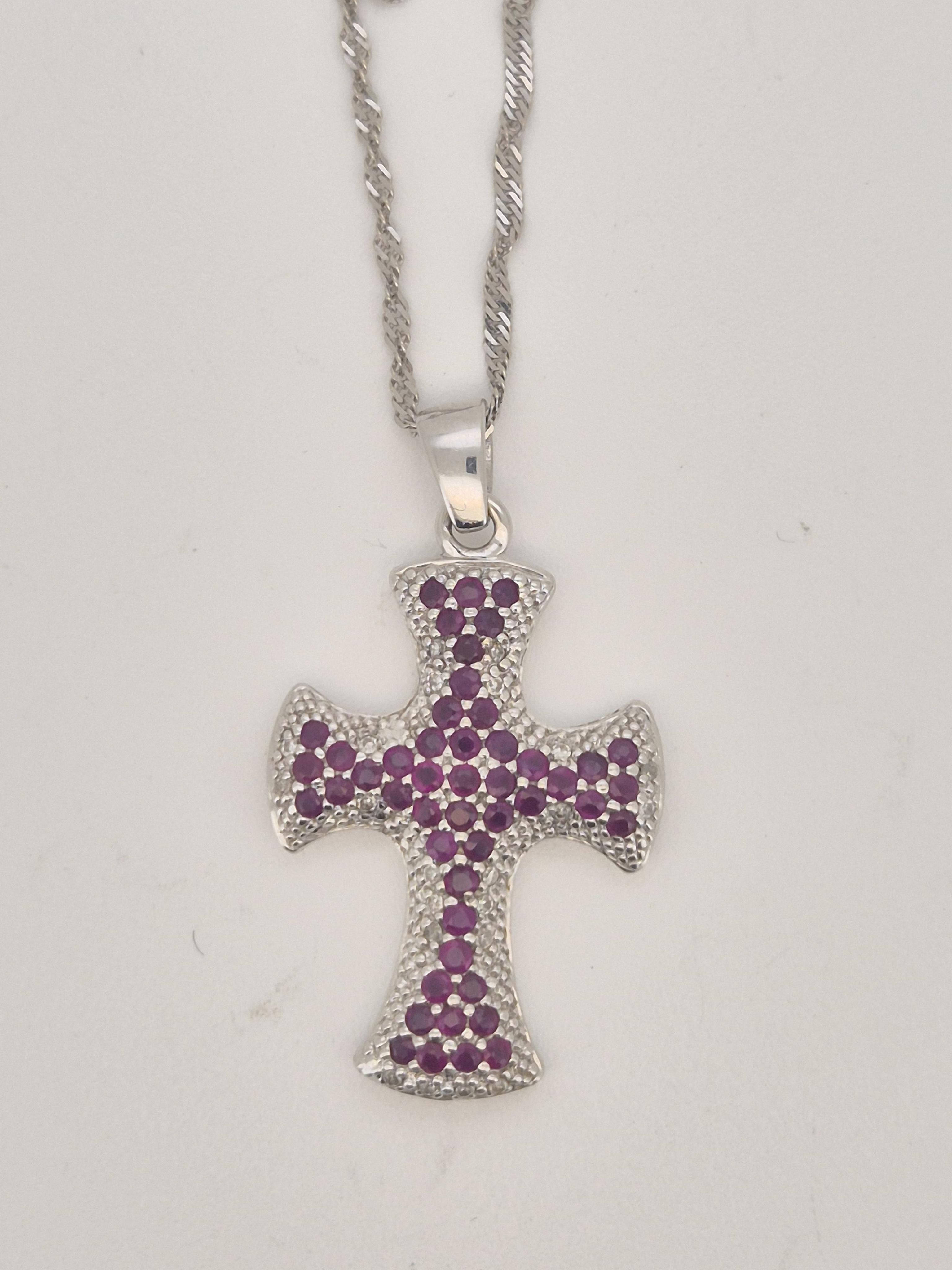 A modern 9ct white gold, ruby and diamond chip cluster set cross pendant, overall 37mm, on a 9ct white gold chain, approx. 44cm, gross weight 7.3 grams.